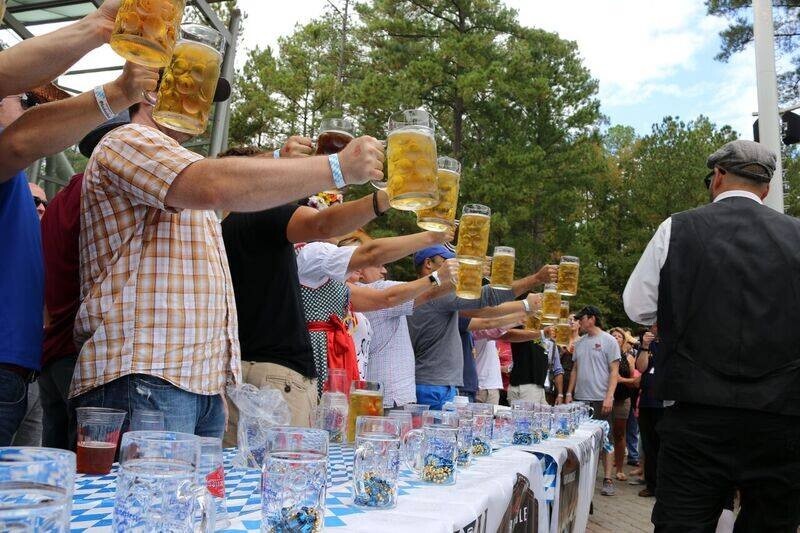 Stein hoisting participants hold up glasses of beer